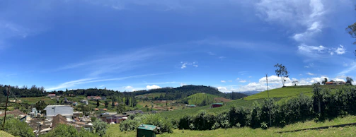 A panoramic view of a peaceful rural estate with green fields and traditional stone buildings under a clear blue sky