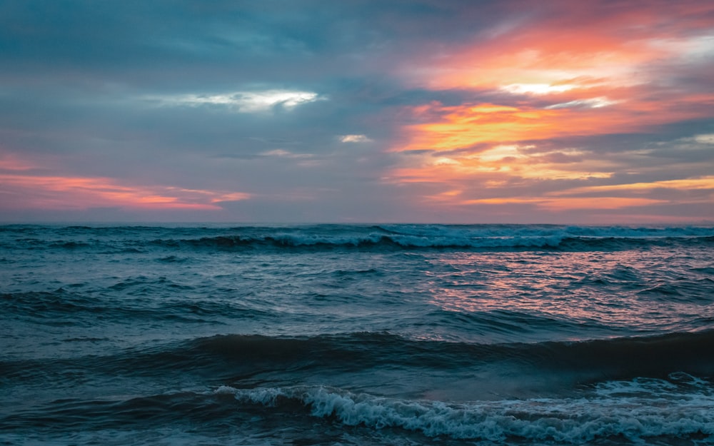 a beautiful sunset over the ocean with waves