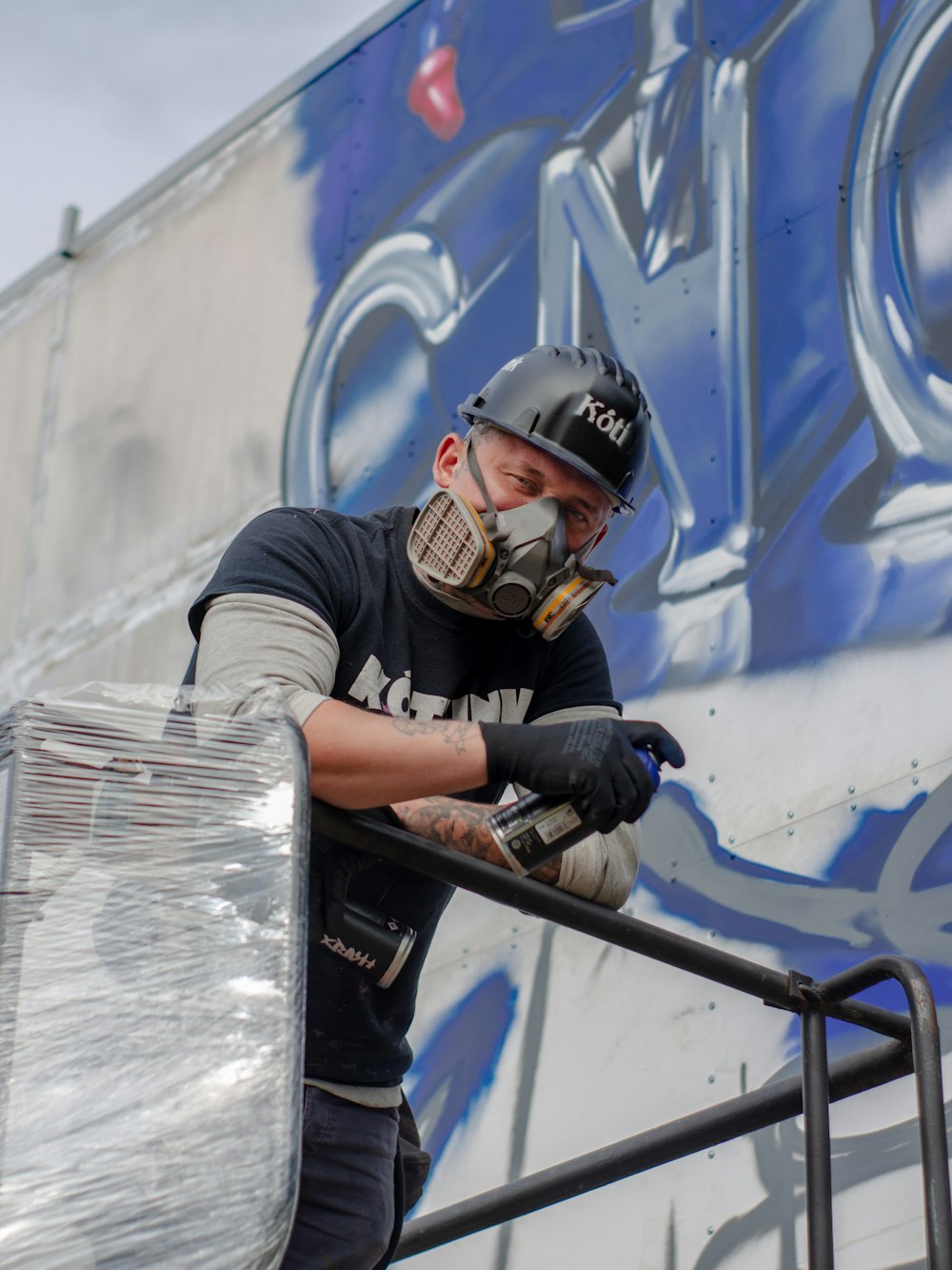 a man in a helmet and protective gear painting a wall