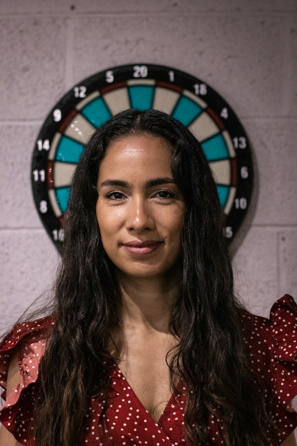 a woman standing in front of a dart board