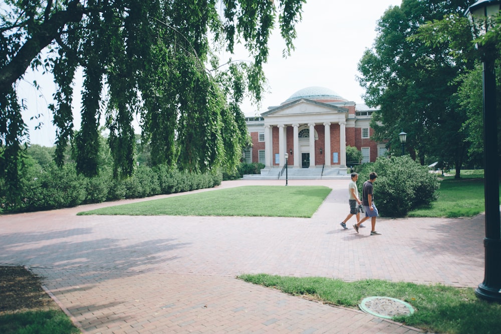 a couple of people walking across a brick walkway