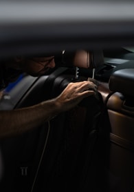 a man sitting in a car with his hand on the steering wheel