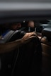 a man sitting in a car with his hand on the steering wheel