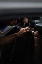 a man sitting in a car with his hand on the steering wheel