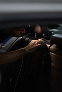 a man sitting in a car with his hand on the steering wheel