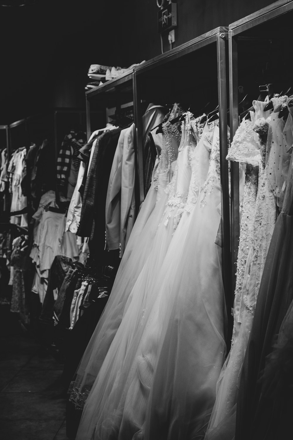 a black and white photo of a rack of wedding dresses
