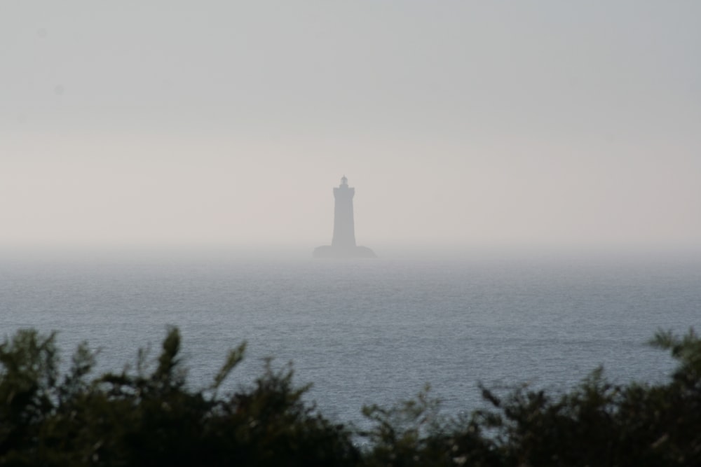 a lighthouse in the middle of the ocean on a foggy day