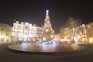 a lit christmas tree in the middle of a plaza