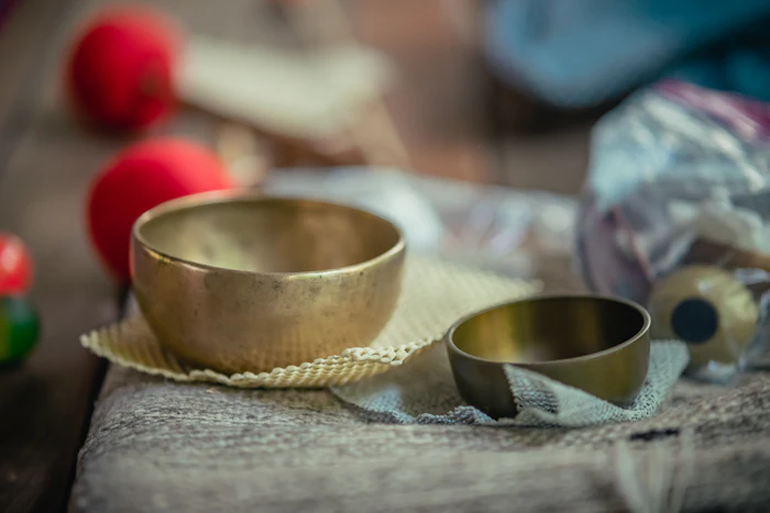 A hammered brass singing bowl with a wooden striker