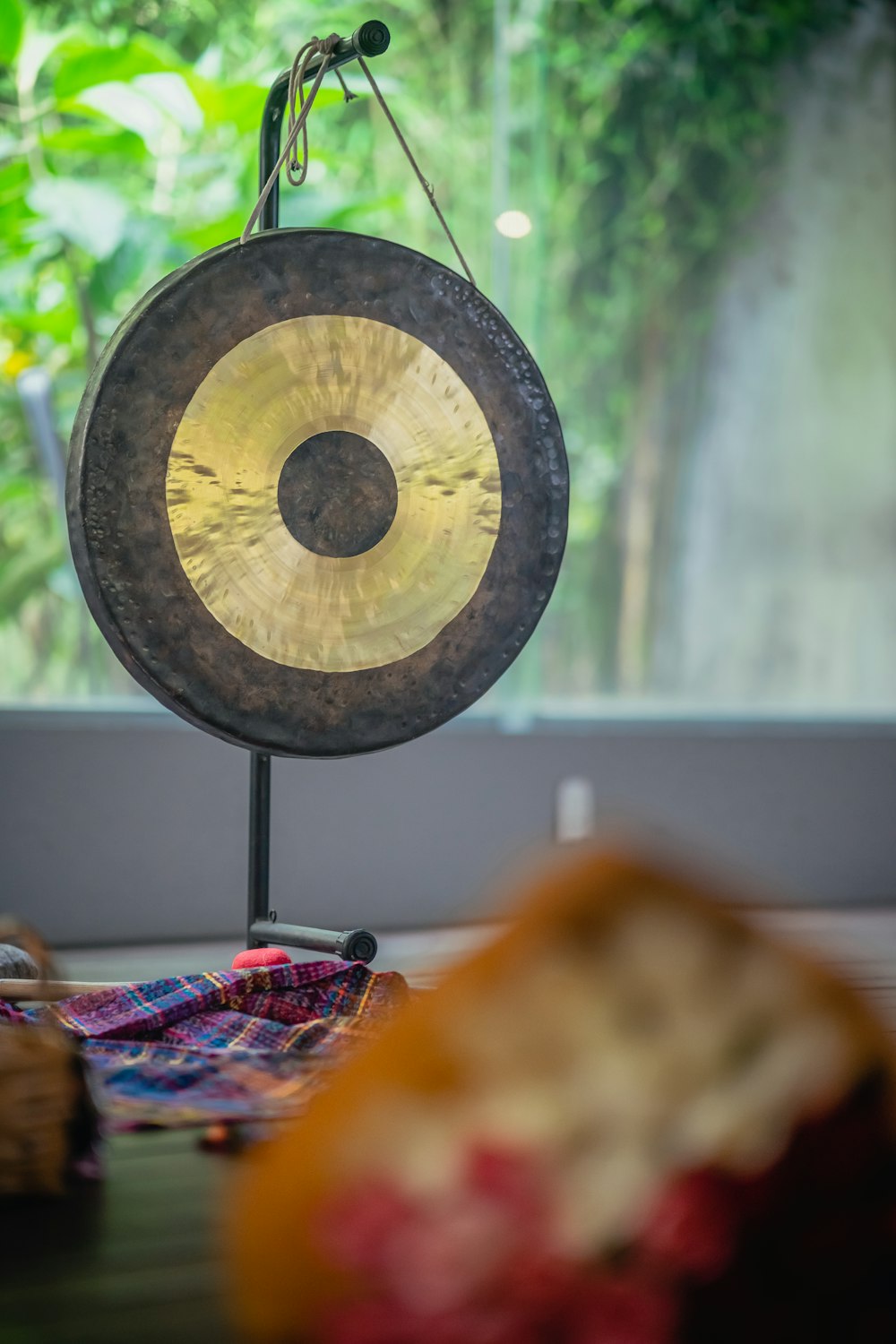 a gong sitting on top of a wooden table next to a window