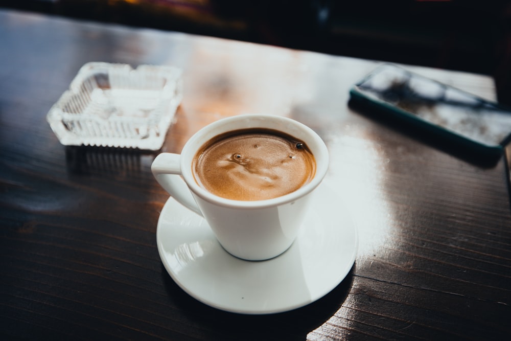 a cup of coffee sitting on top of a wooden table