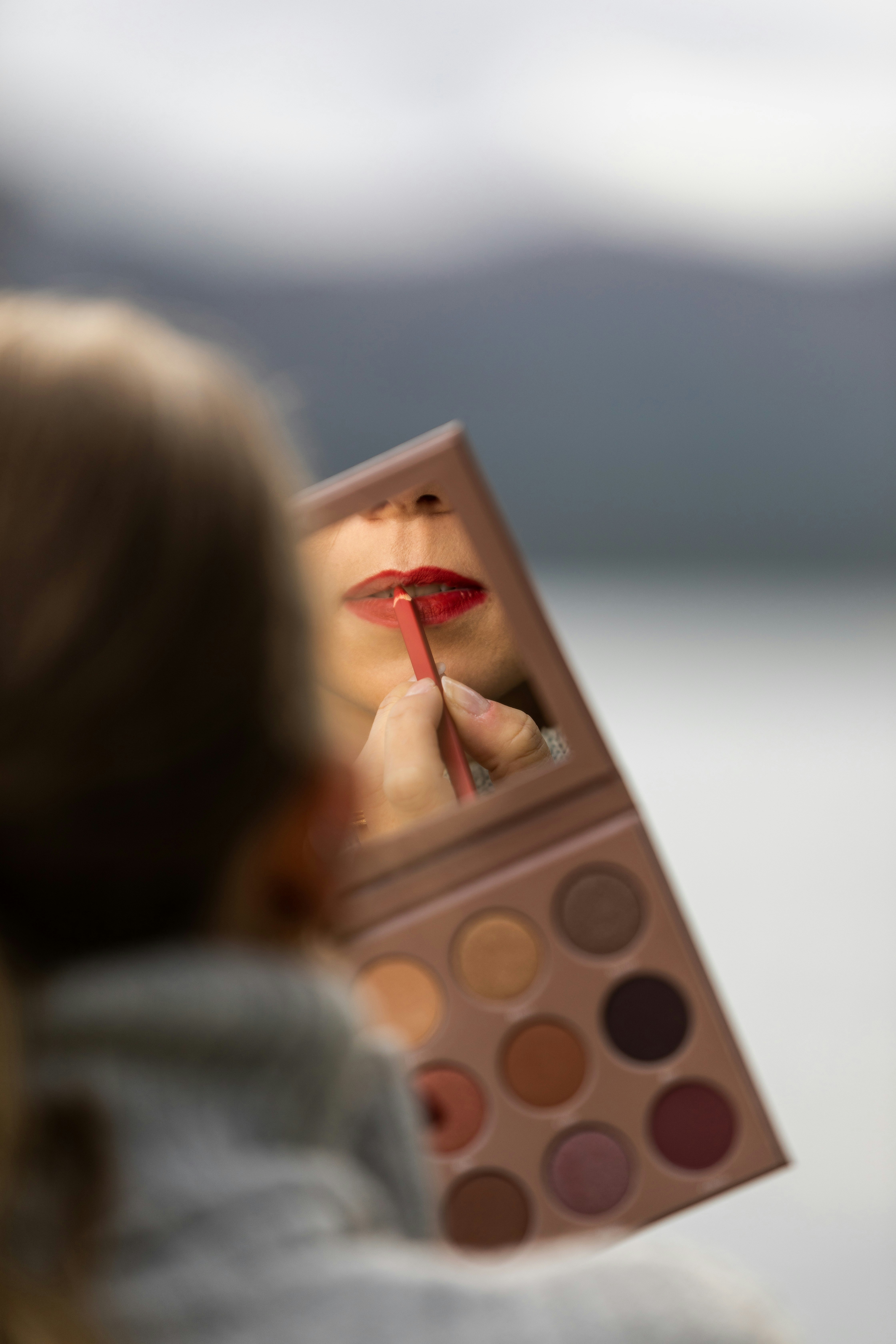 a woman holding a palette of makeup in front of her face