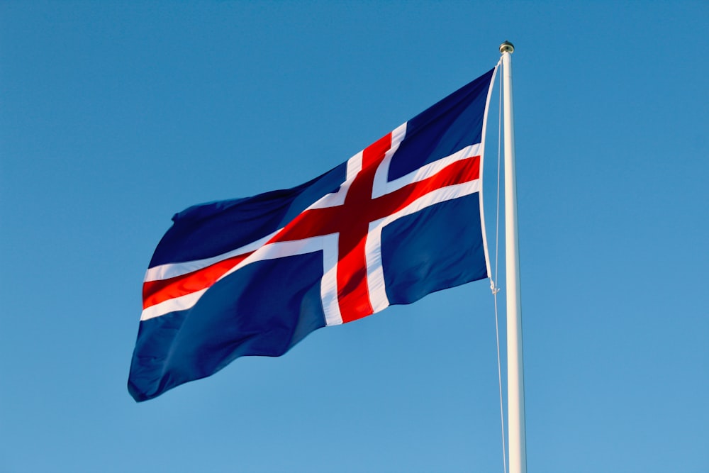 a flag flying in the wind with a blue sky in the background