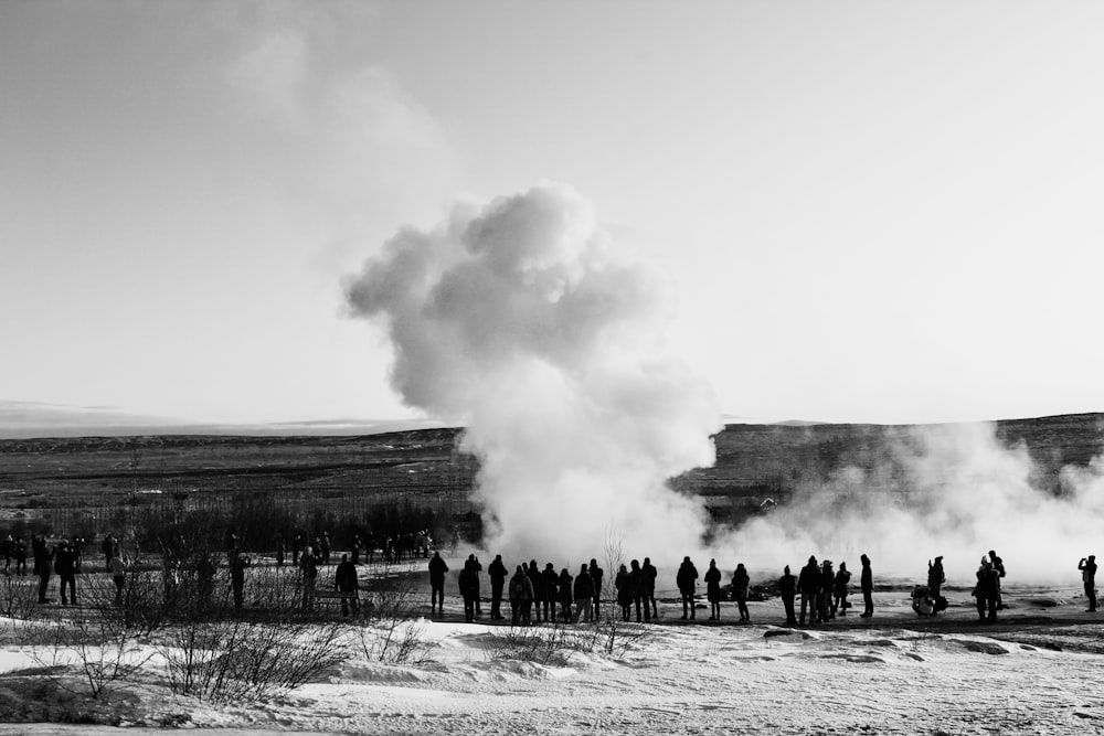 a group of people standing in front of a geyser