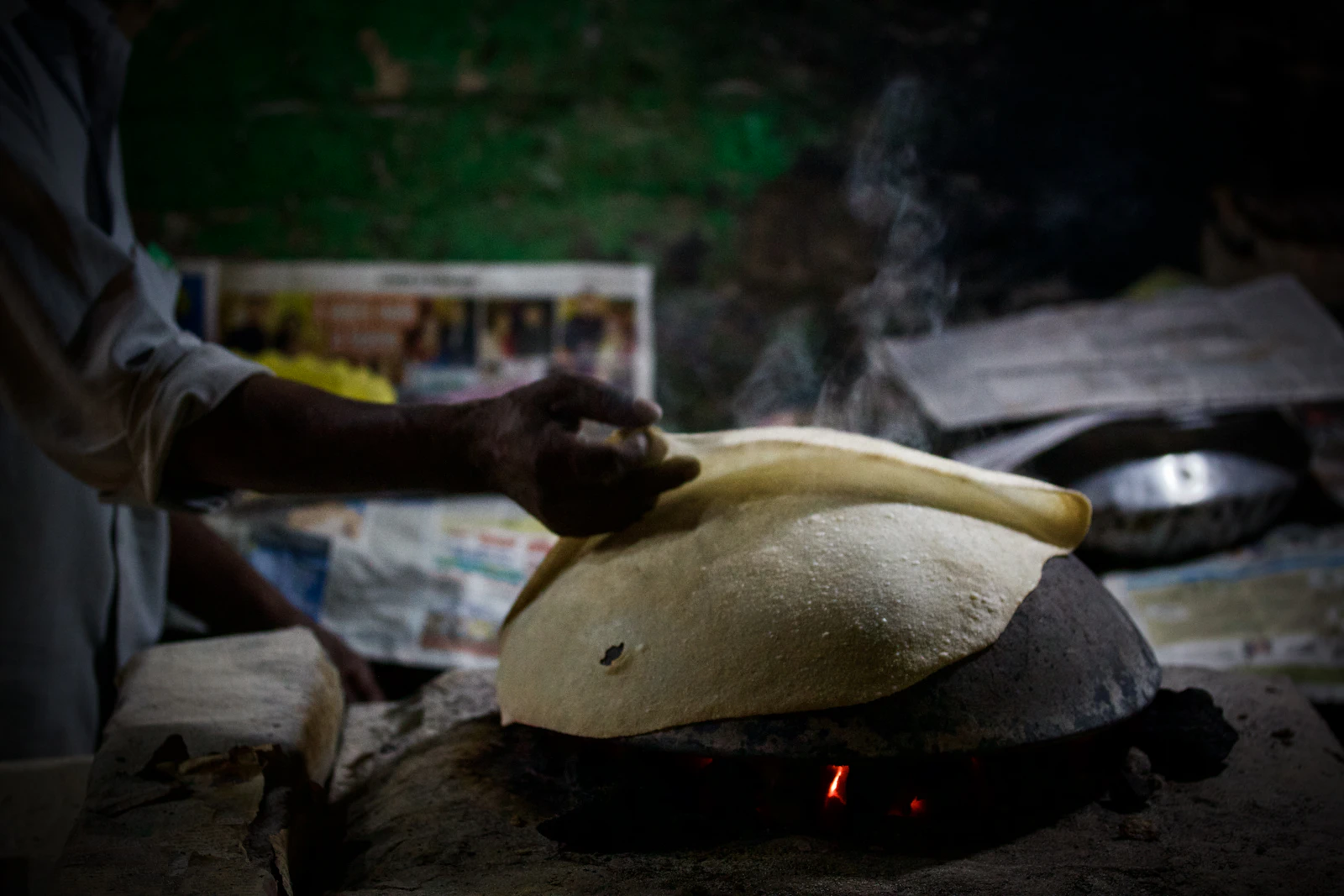 Chef stretching naan dough beside the tandoor