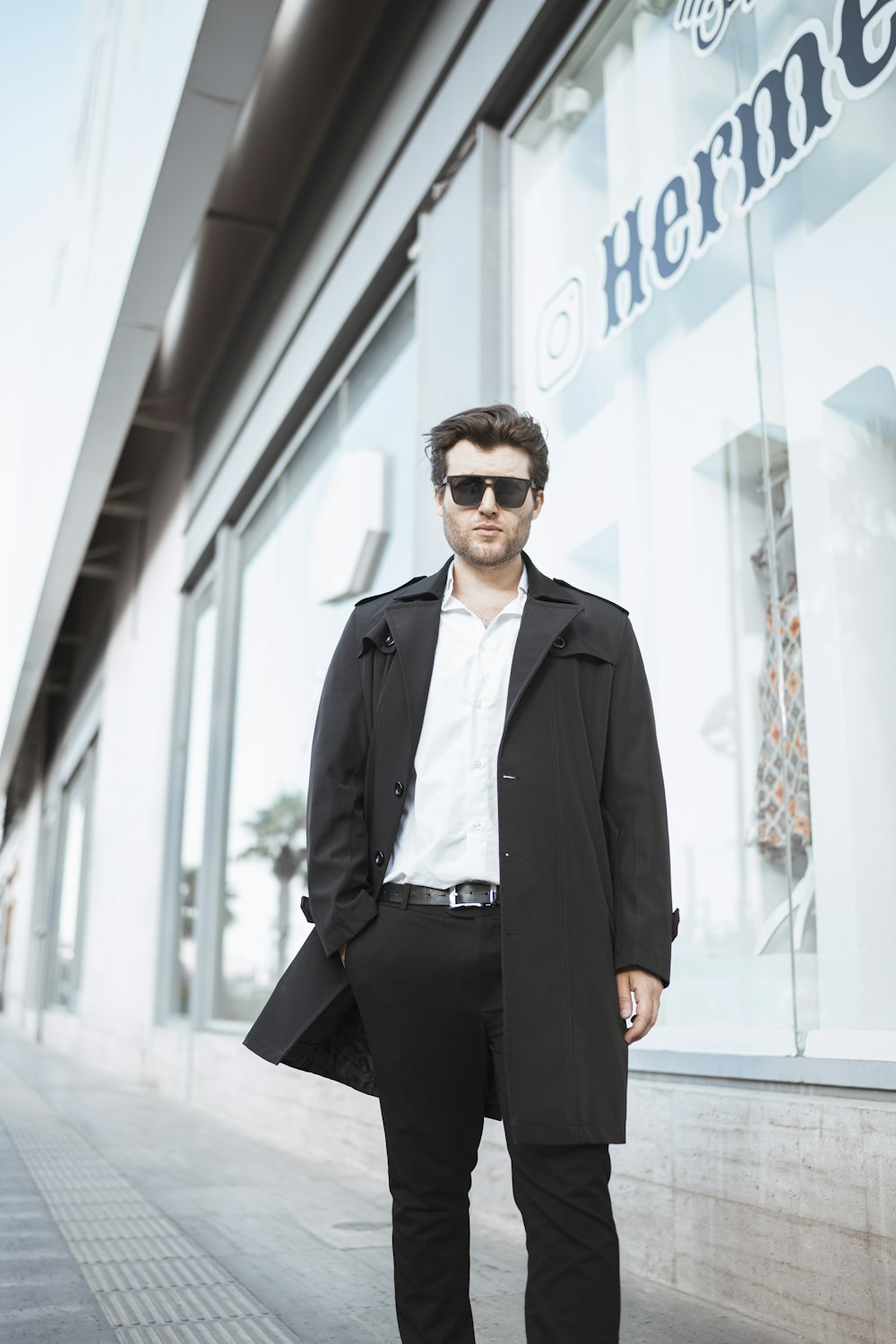 a man standing in front of a building wearing sunglasses