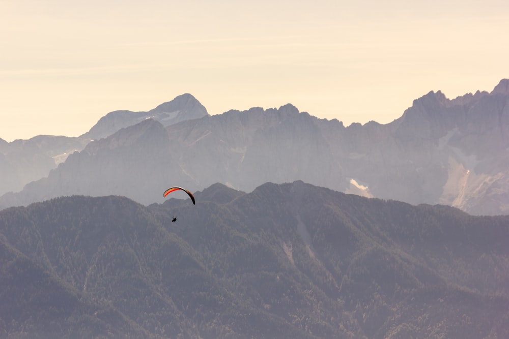 a paraglider glides over a mountain range