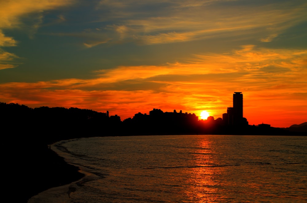 a sunset over a body of water with buildings in the background