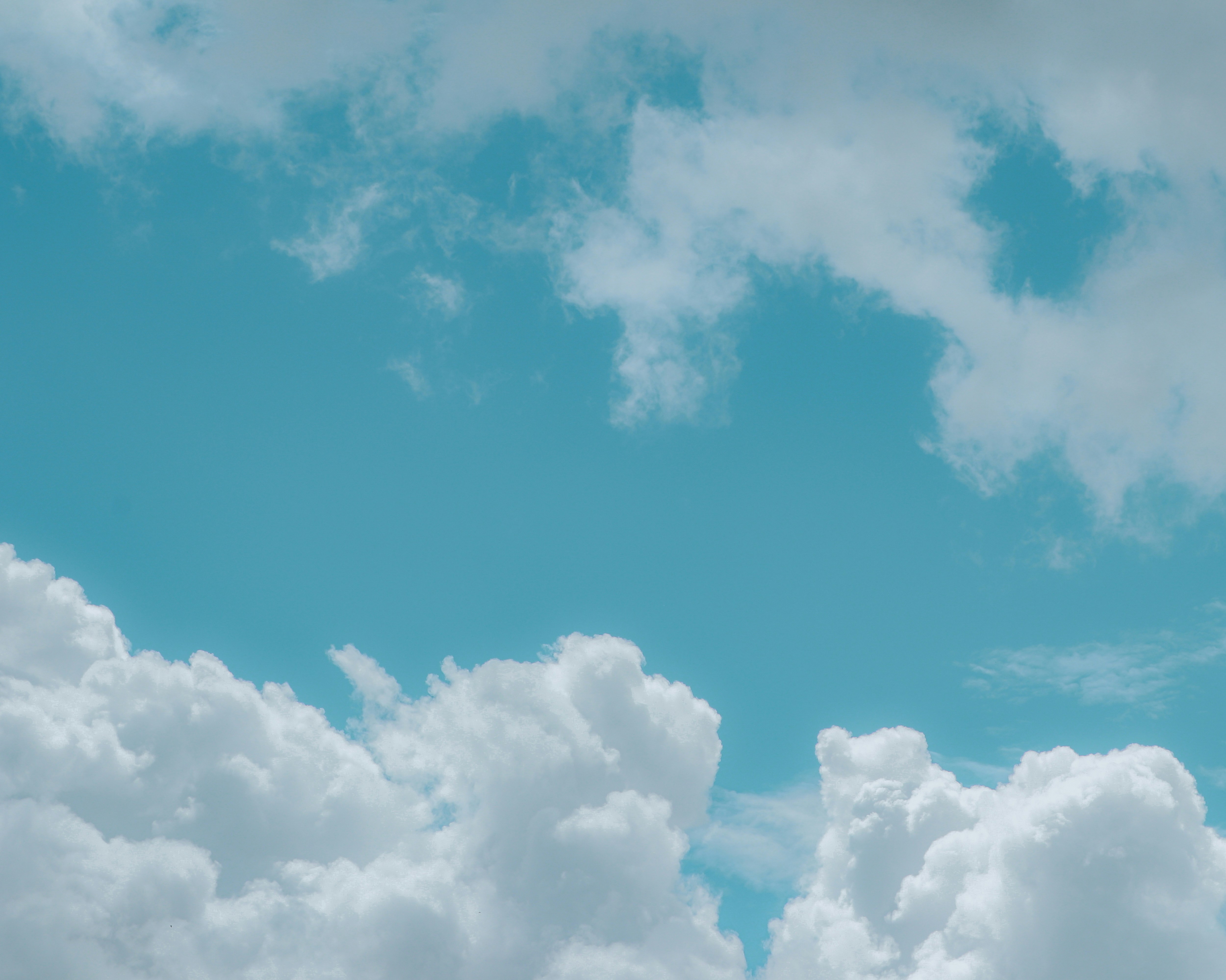 a plane flying through a cloudy blue sky