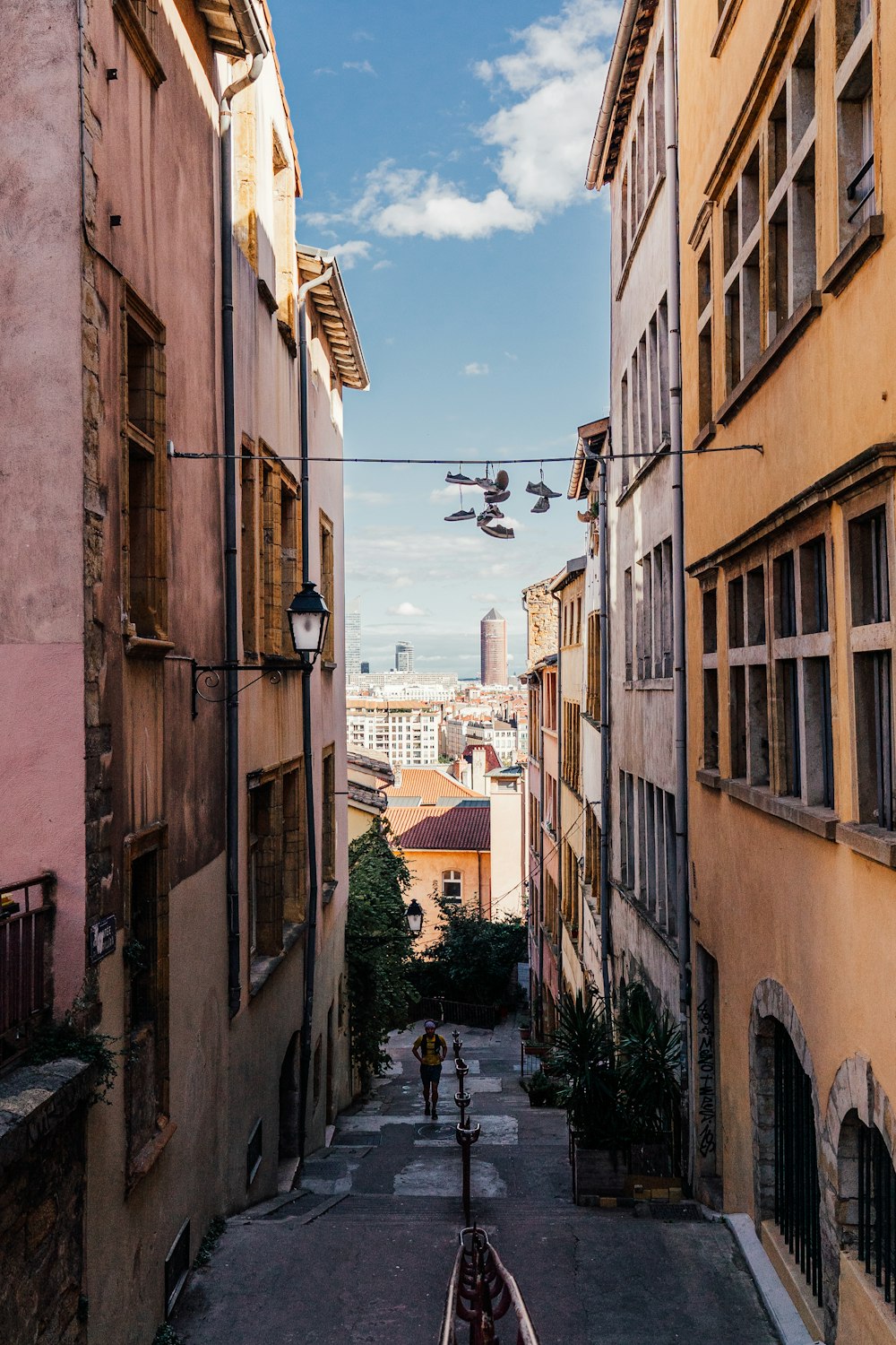 a view of a narrow street with a plane flying overhead