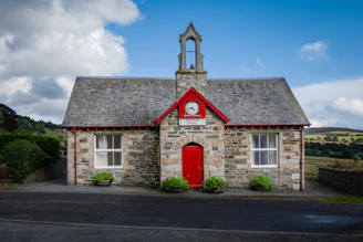 a small stone building with a clock on the front