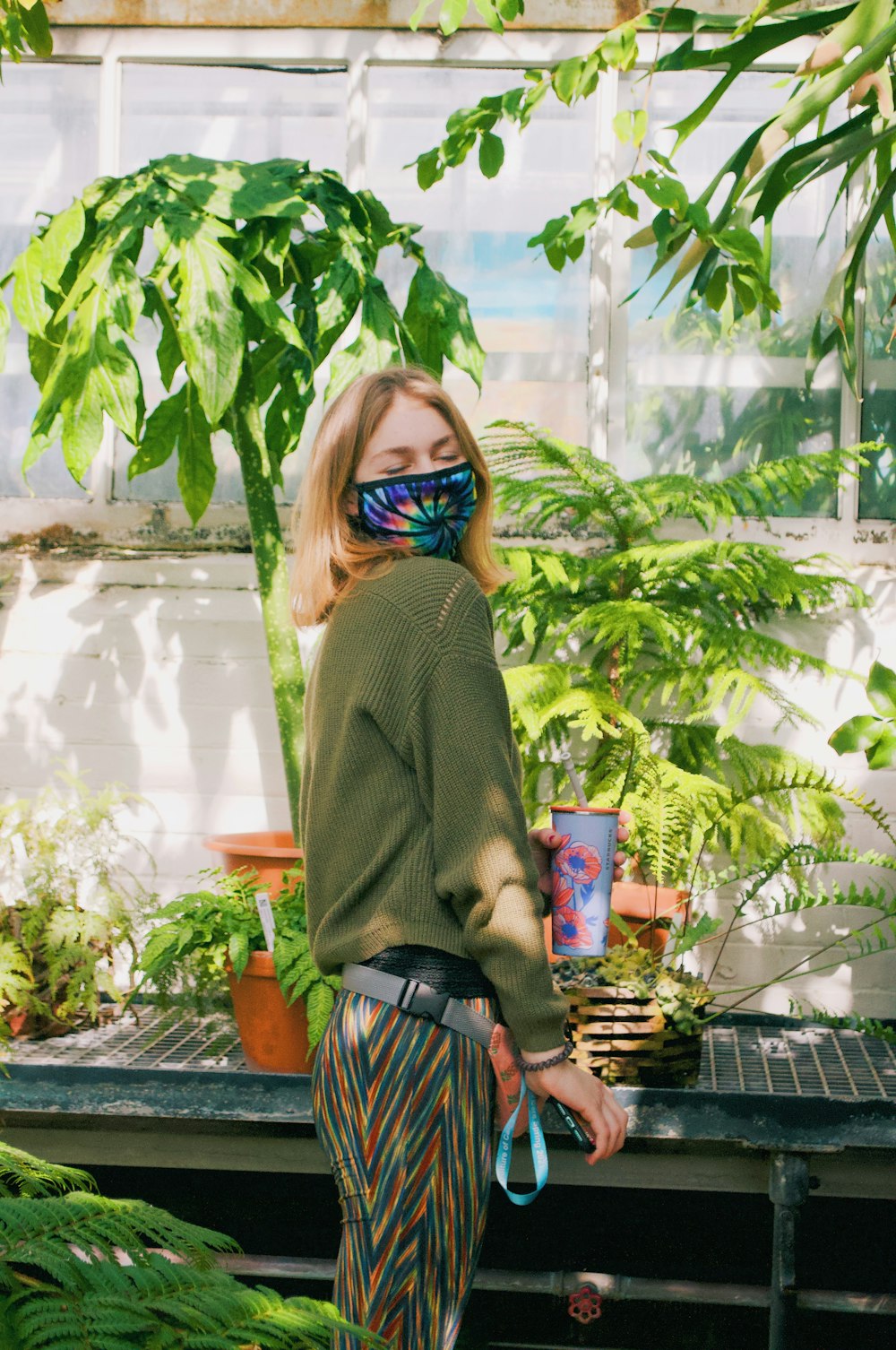 a woman in a green sweater is wearing a mask