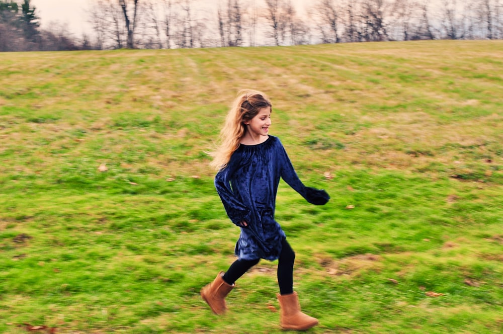 a young girl is running in a field