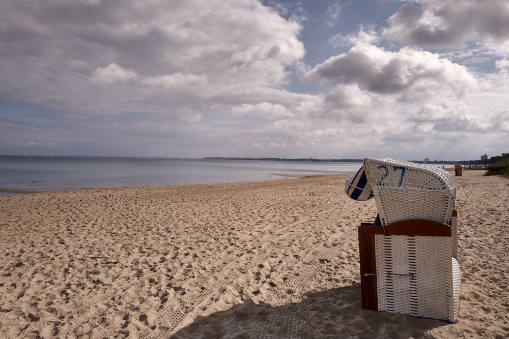 una sedia bianca seduta sulla cima di una spiaggia sabbiosa