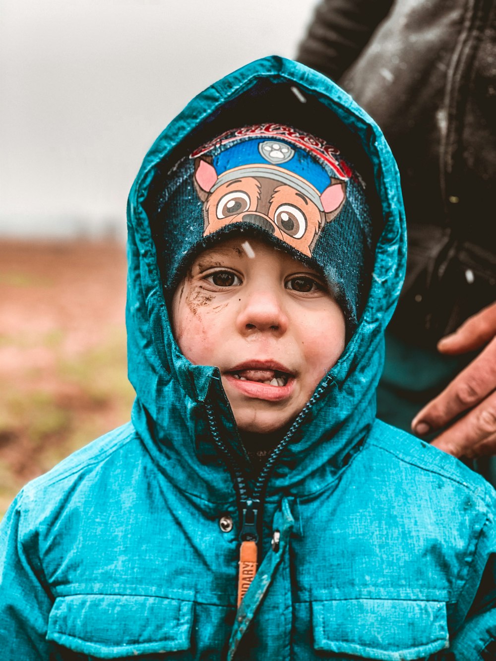 a young boy wearing a blue jacket and a hat