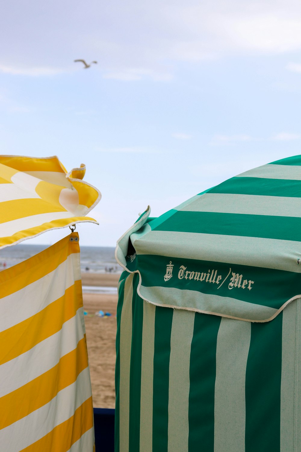a green and white striped umbrella and a yellow and white striped beach chair