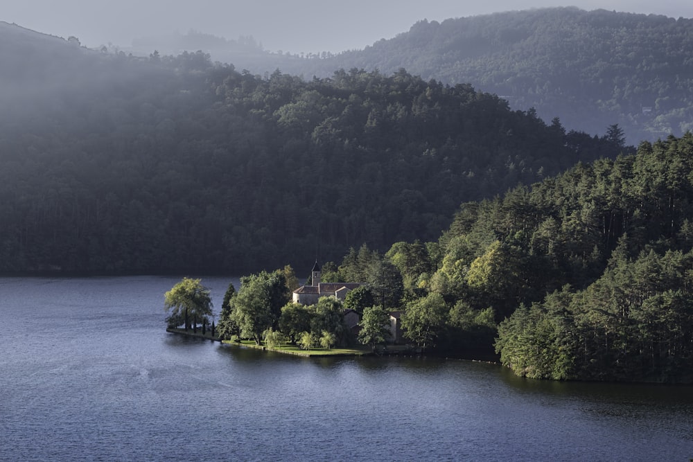 a lake surrounded by trees with a house in the middle