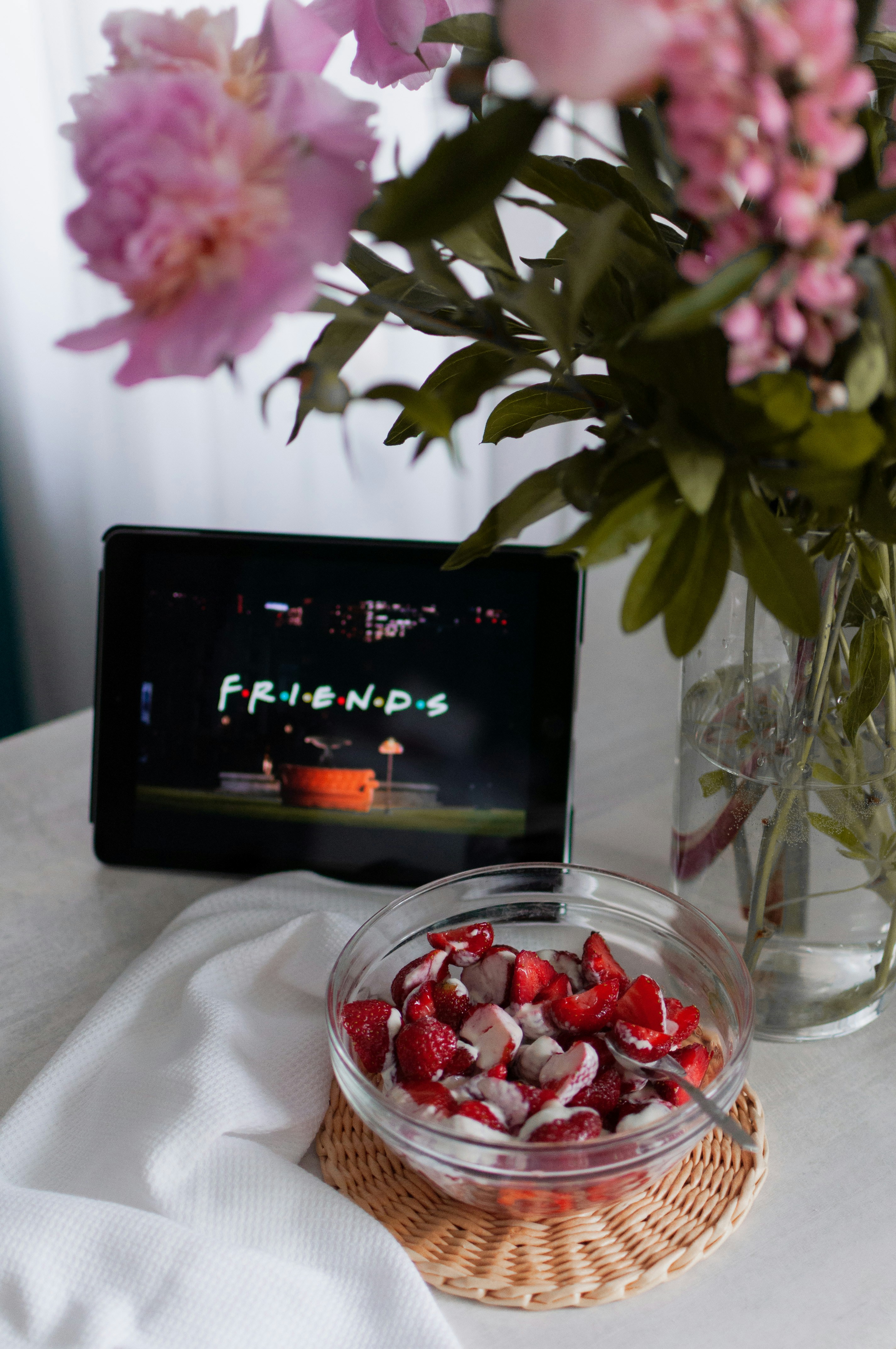 a bowl of strawberries and a vase of flowers on a table