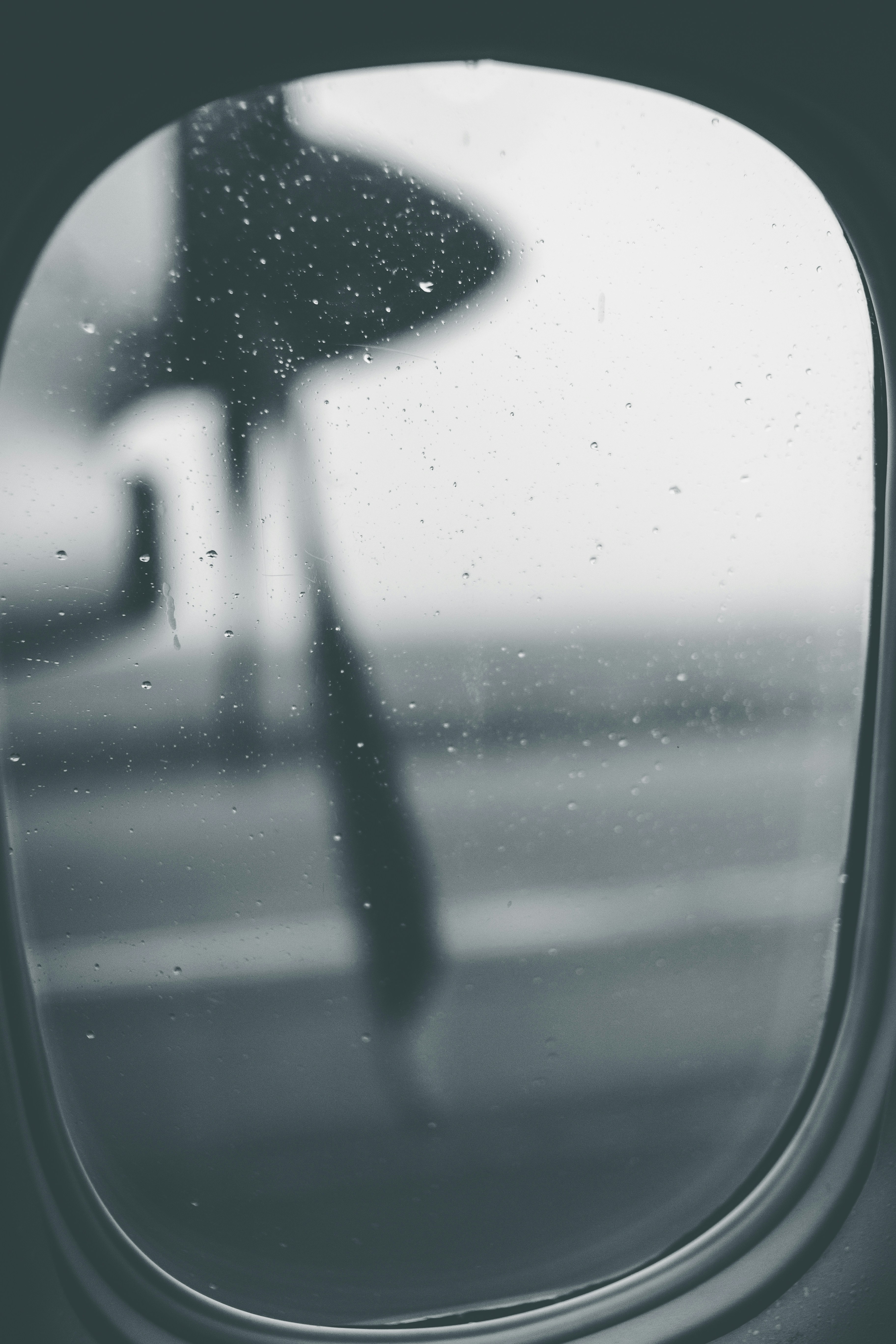 an airplane window with a person holding an umbrella