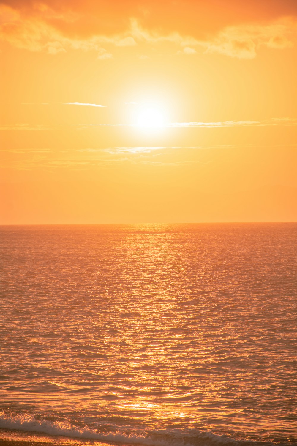 the sun is setting over the ocean on the beach