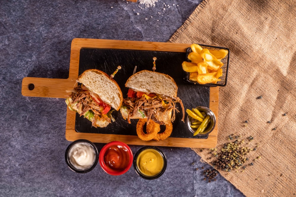 a wooden cutting board topped with two sandwiches