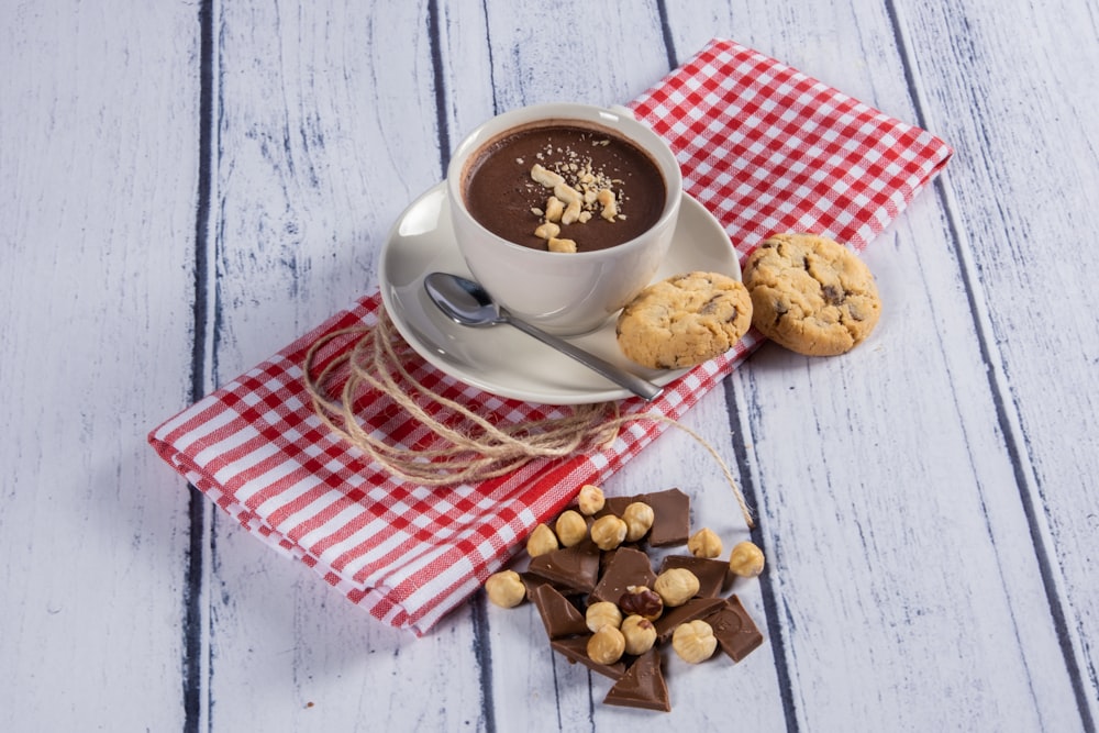 uma xícara de chocolate quente e biscoitos em um guardanapo xadrez vermelho e branco