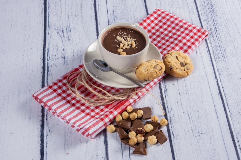 a cup of hot chocolate and cookies on a red and white checkered napkin