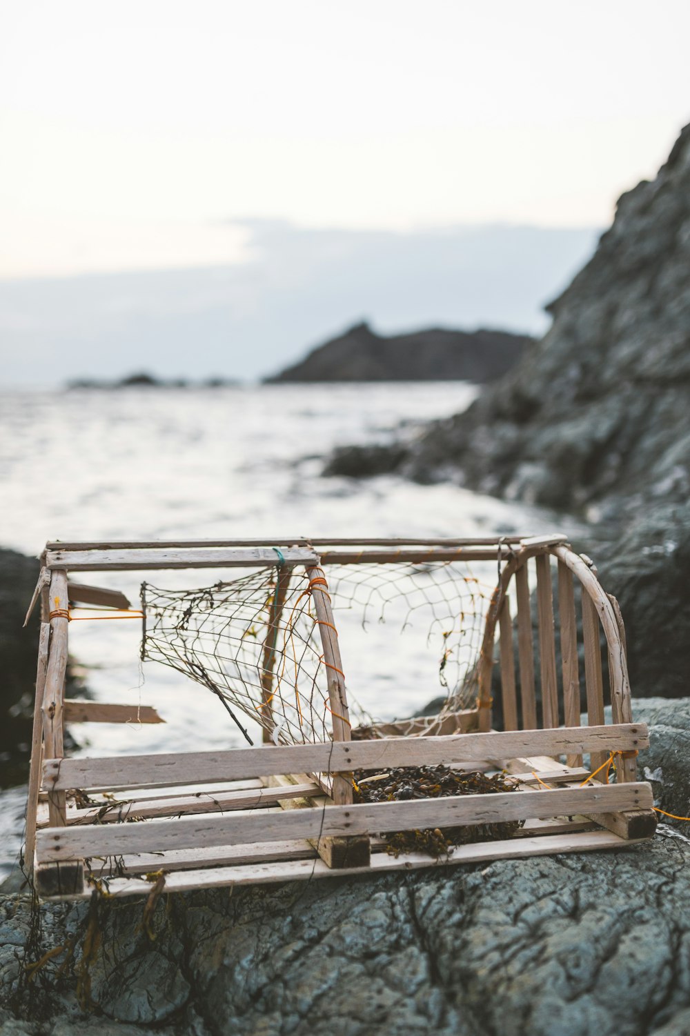 a wooden box sitting on top of a rock next to the ocean