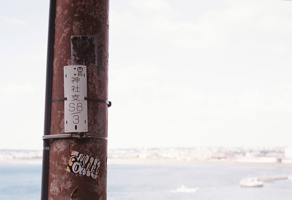 a pole with some stickers on it next to a body of water