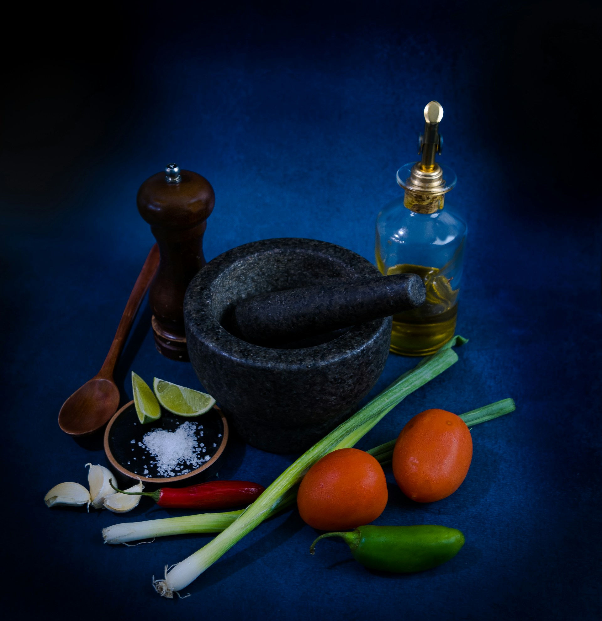 a mortar, pepper, garlic, lime, and pepper shaker on a blue