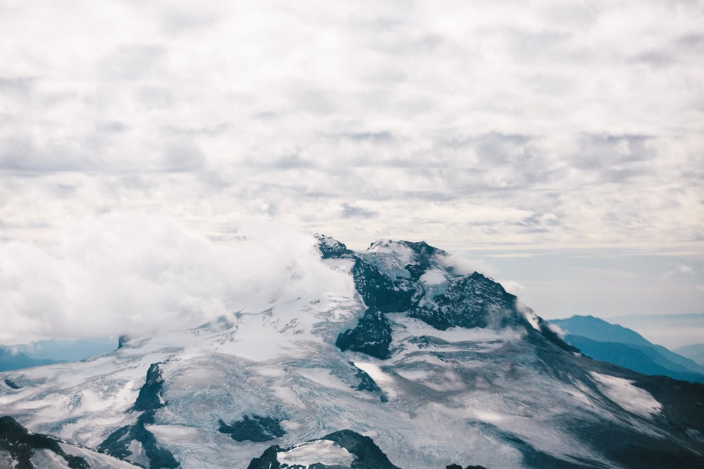 a mountain covered in snow under a cloudy sky