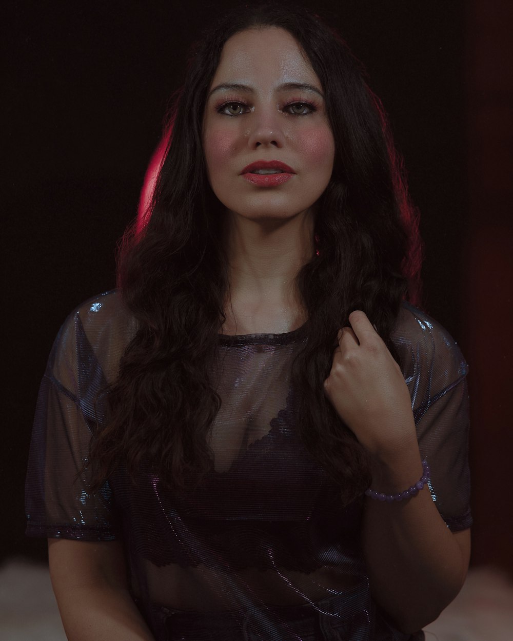a woman with long dark hair wearing a sheer top