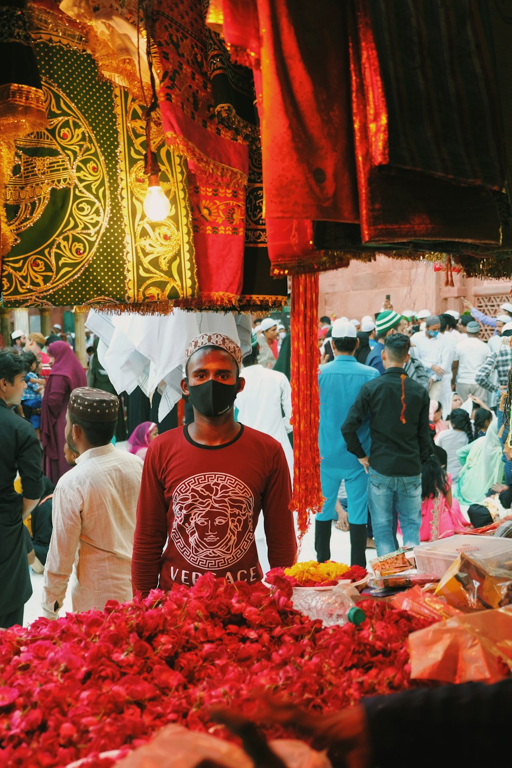 Ein Mann mit Gesichtsmaske steht vor einem Blumenstrauß