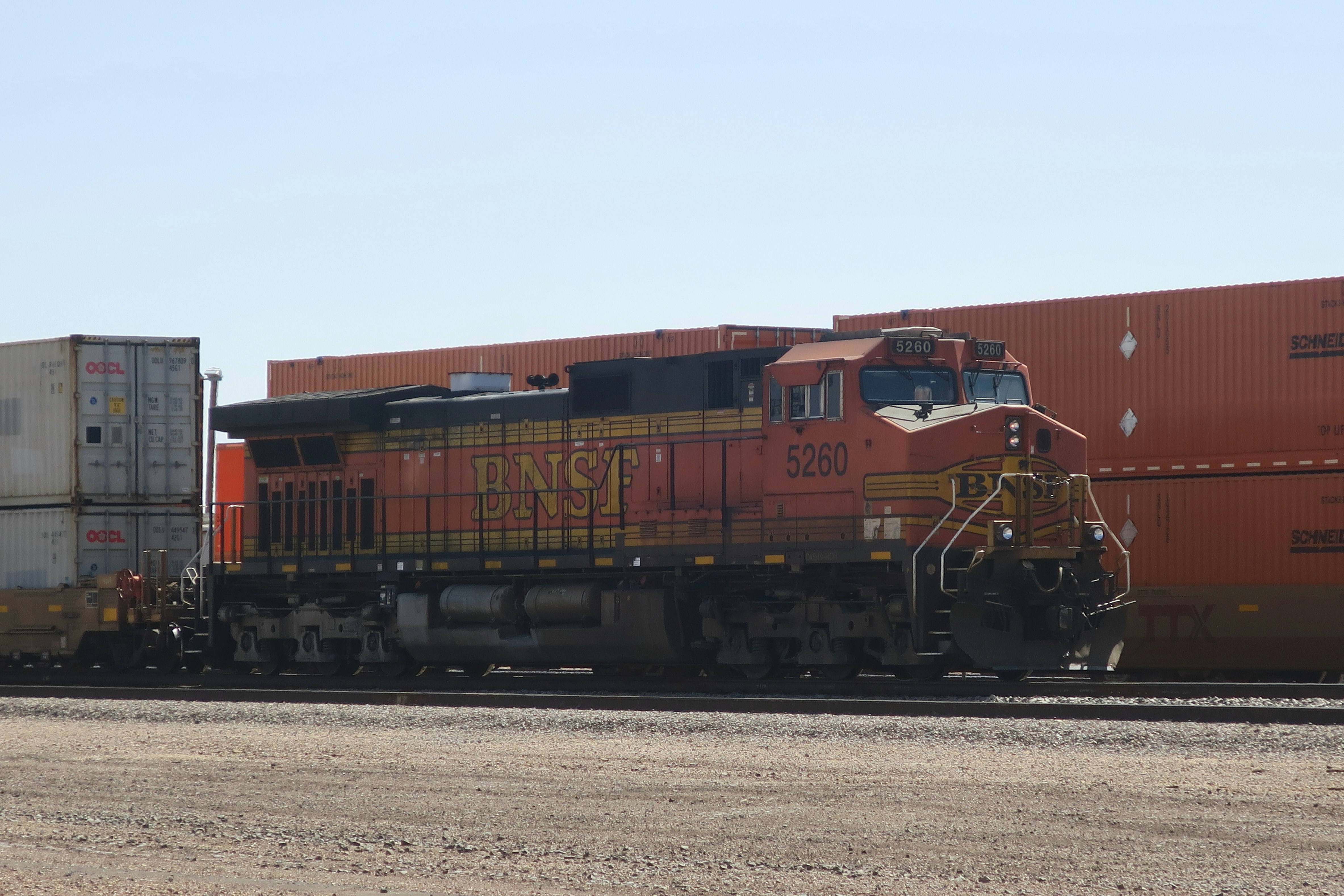 Ein Zug, der neben einem Feld die Bahngleise hinunterfährt
