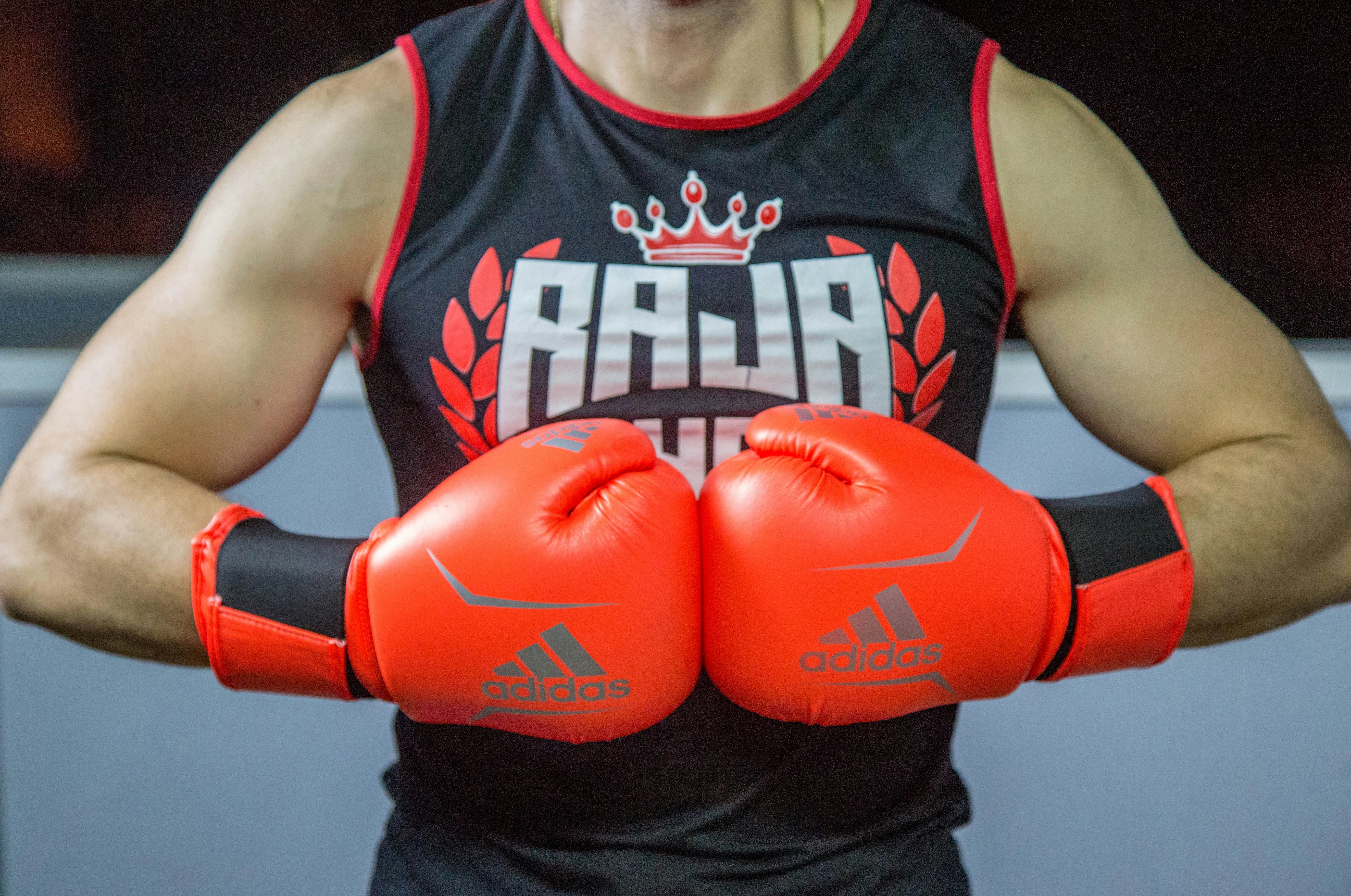 A person wearing bright red boxing gloves and a sleeveless top, demonstrating a boxing stance, related to choosing beginner boxing gloves.