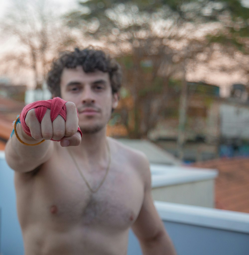 a shirtless man pointing a finger at the camera