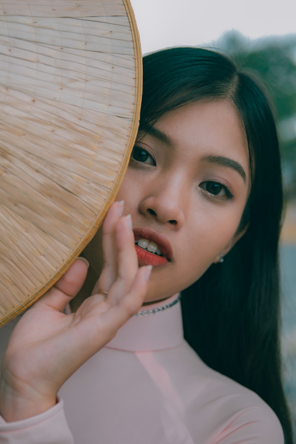 a woman in a pink shirt holding a bamboo fan