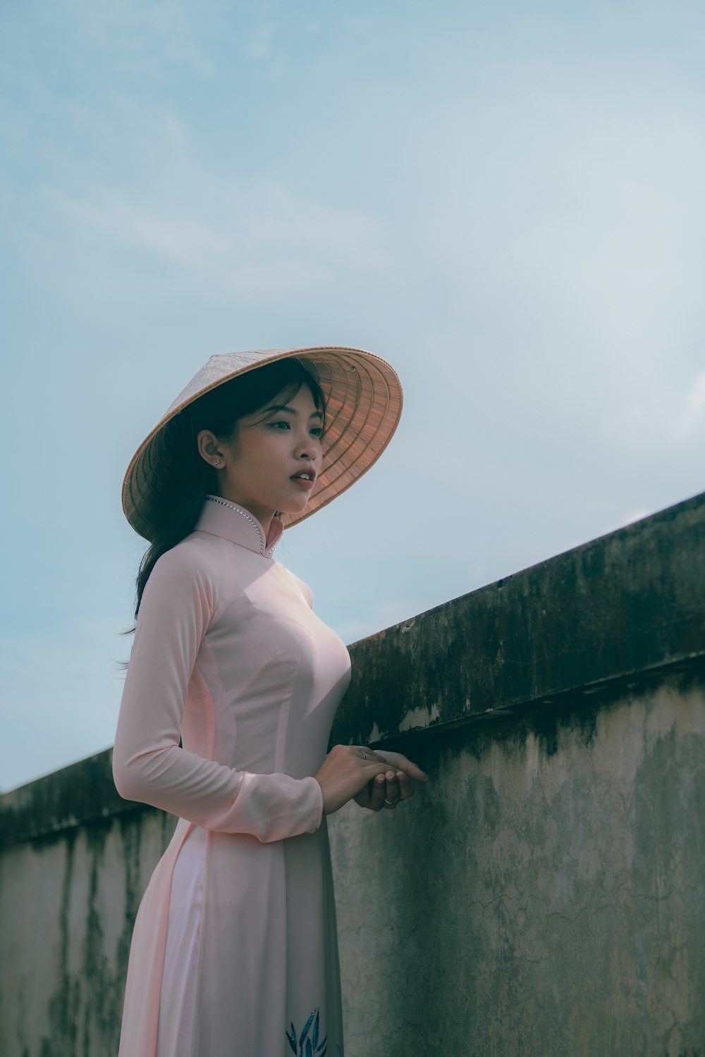 a woman wearing a hat leaning against a wall