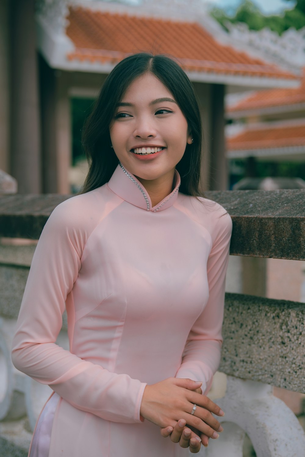 a woman in a pink dress standing next to a wall