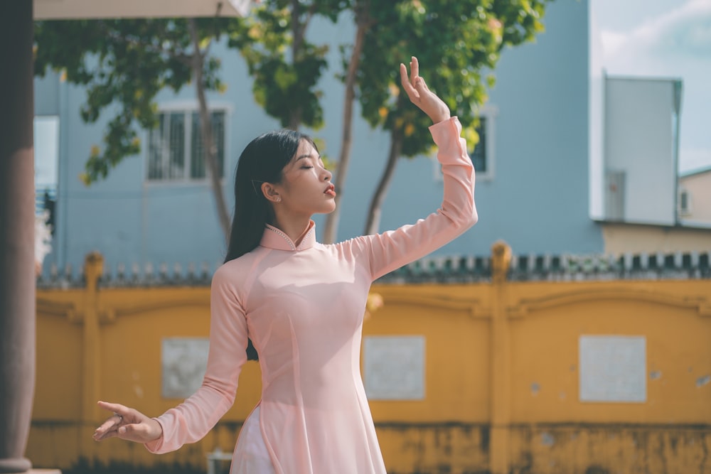 a woman in a pink dress is holding her arms out